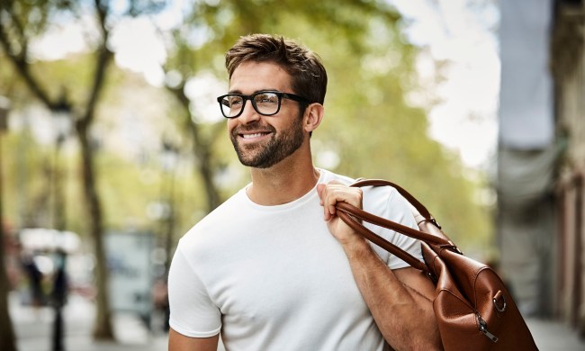 Smiling businessman with brown bag walking in city