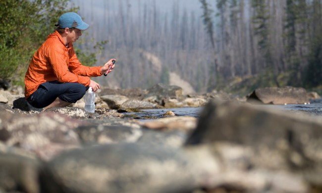 Young man checks water filter alongside river